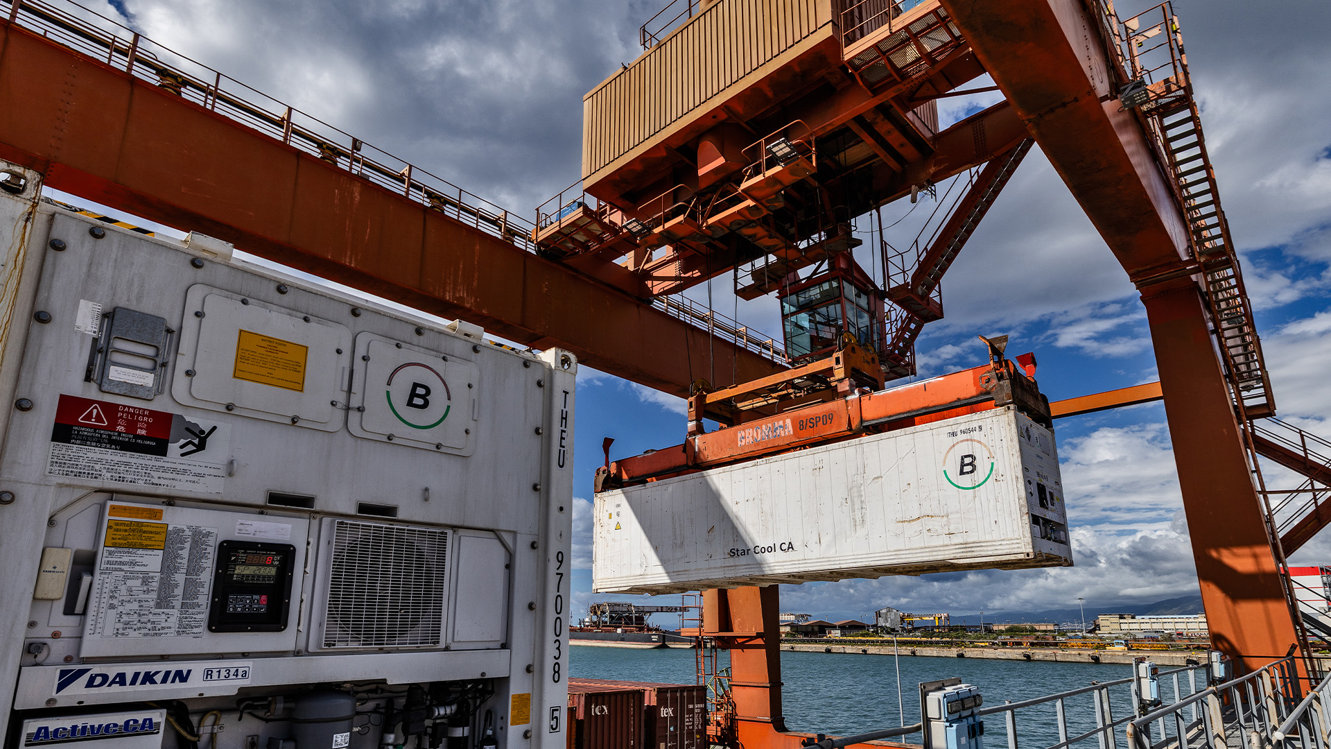 Un container refrigerato che viene trasportato da una gru