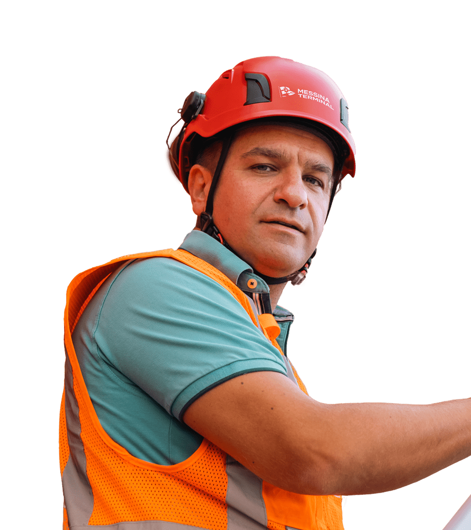 Portrait of a man in charge of Messina Terminal security boarding one of the ships of the Messina Line fleet, wearing a teal polo shirt, an orange high-visibility vest and a red safety helmet with the ‘Messina Terminal’ logo. The man looks up with a concentrated expression