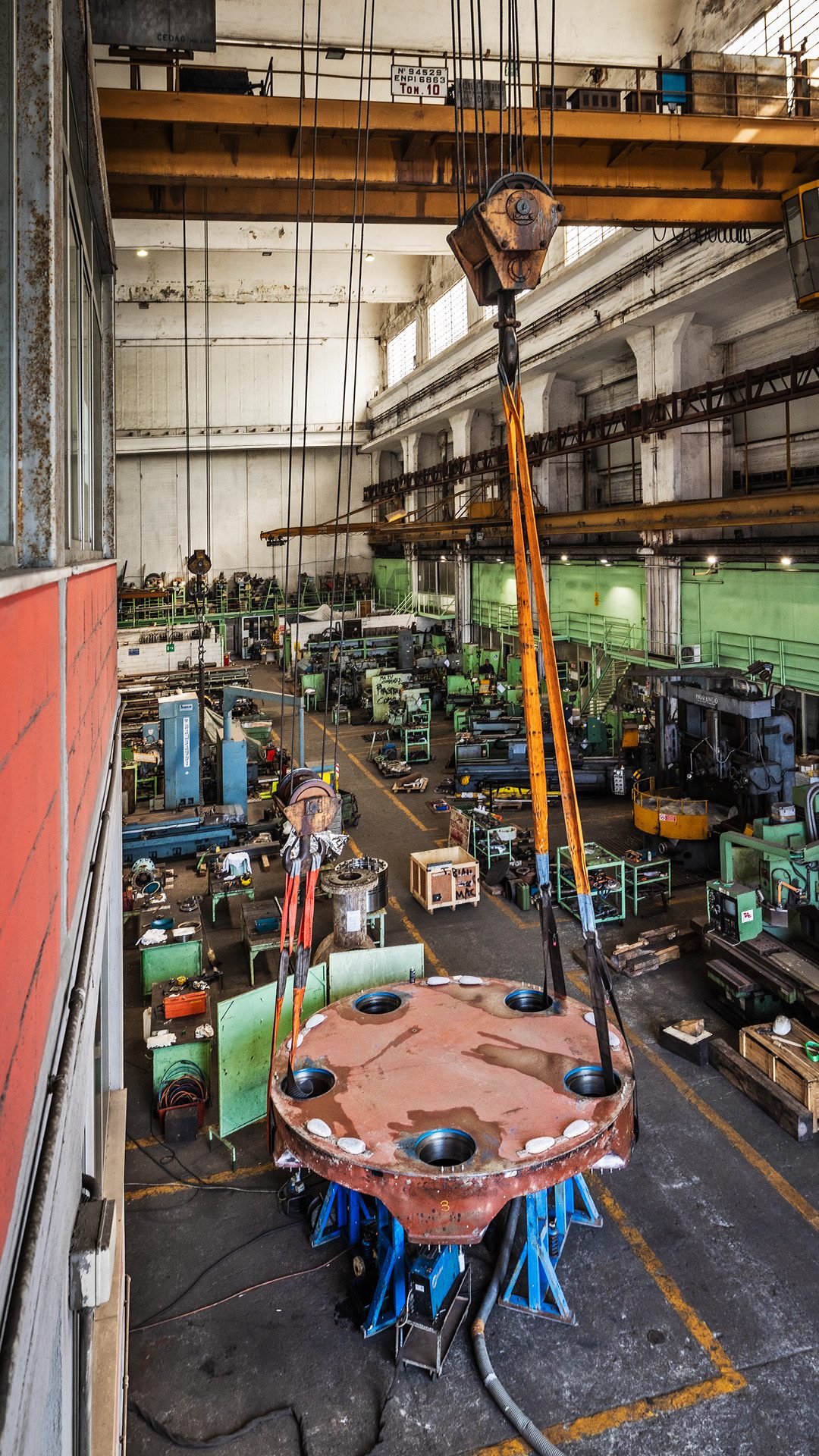 Panoramica del cantiere navale con una gru che sta spostando un pesante componente di una nave